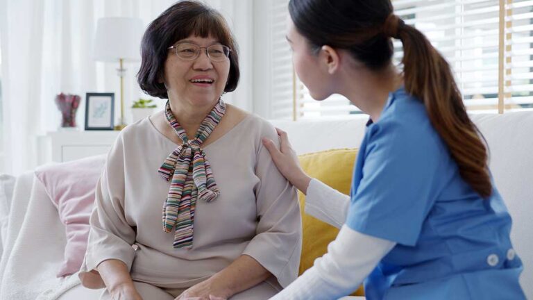 A family visits an elderly woman in a comfortable assisted living community lounge.