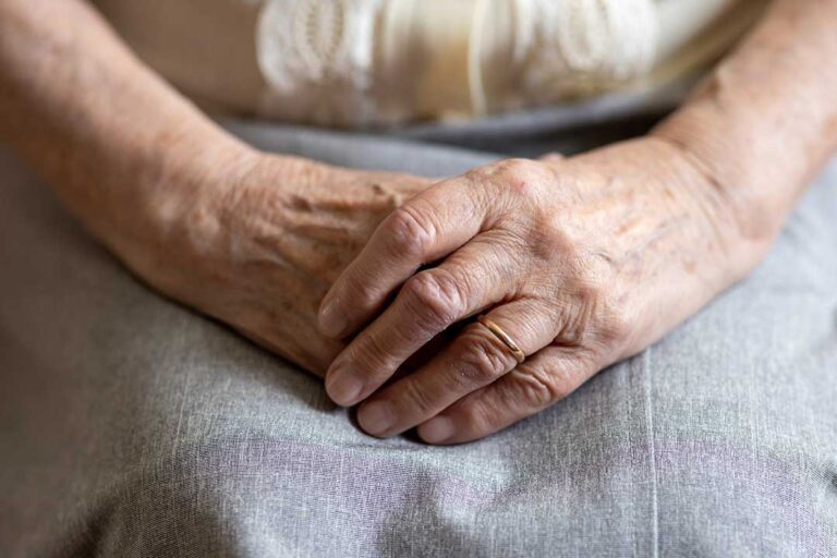 Older adult and family member arranging labeled clothing and photos in a bright assisted living room.
